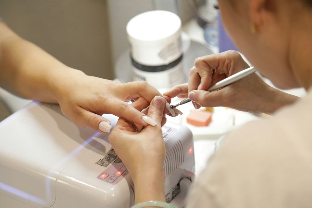Manicurista arreglando las uñas de una clienta en un salón