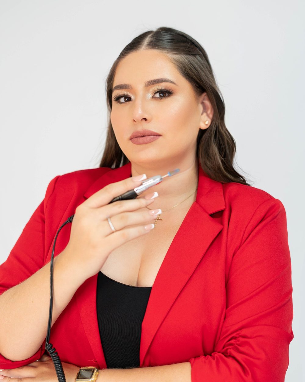 Manicurista con blazer rojo sosteniendo su torno de uñas